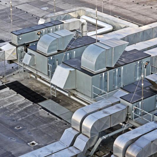 Luftaufnahme von komplexen mechanischen Dachinstallationen mit Lüftungsrohren und Klimageräten.