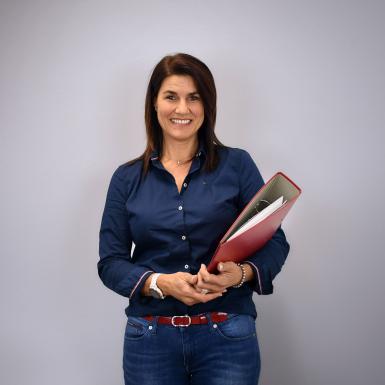 Porträt von Büroassistentin Beate Schoder mit Ordner im Arm