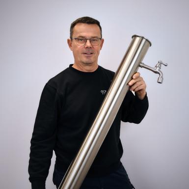 Porträt von Versandmitarbeiter Franz Haunschmid mit Wassersäule 