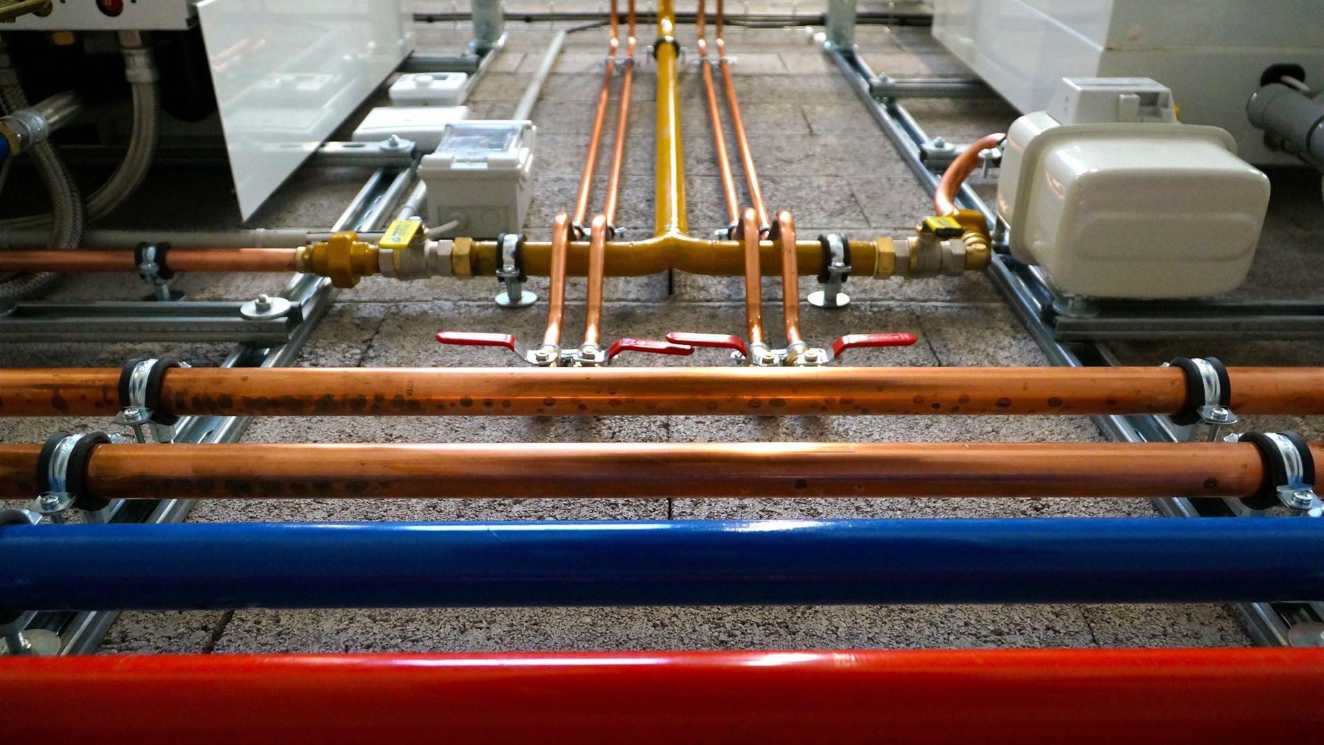 Ein Ensemble von Rohren unterschiedlicher Materialien und ein komplexes Kupferrohrverteilungssystem in einer technischen Umgebung.